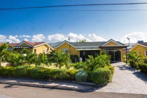 ein großes gelbes Haus mit Bäumen und Sträuchern in der Unterkunft Sweet Holiday Haven in Ocho Rios