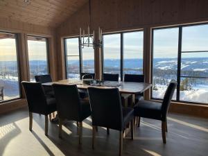 uma sala de jantar com mesa, cadeiras e janelas em Løstegård Hytter em Gol