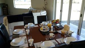 a dining room table with plates and dishes on it at 5 Acres B&B in Tokoroa