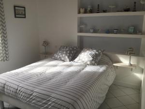 a bedroom with a bed with a striped comforter at Maison de standing style rethais in Le Bois-Plage-en-Ré