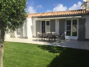 a house with a table and chairs on a patio at Maison de standing style rethais in Le Bois-Plage-en-Ré