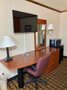 a desk with a television and a chair in a hotel room at Green bird Inn in Vernon