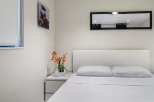 a white bedroom with a white bed and a mirror at Alani Bay Condos in Fort Lauderdale