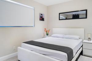 a white bedroom with a bed and a mirror at Alani Bay Condos in Fort Lauderdale