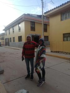 two people standing on a sidewalk in front of a building at Pumamarka House in Ollantaytambo