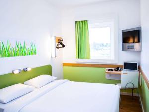 zieloną i białą sypialnię z łóżkiem i oknem w obiekcie ibis budget Campo Grande w mieście Campo Grande
