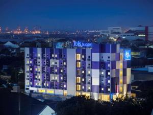 een gebouw met een blauwe en witte gevel 's nachts bij Ibis Budget Semarang Tendean - CHSE Certified in Semarang