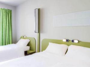 - une chambre avec 2 lits blancs et un rideau vert dans l'établissement Ibis Budget Braga Centro, à Braga