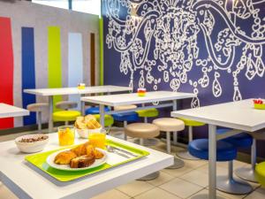 a cafeteria with tables and chairs with a plate of food at ibis budget Vienne Sud in Vienne