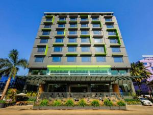 ein hohes Gebäude mit grünen und gelben Fenstern in der Unterkunft Hotel Stadium in Yangon