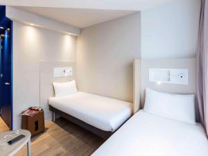 a small room with two beds and a table at ibis budget Amsterdam City South in Amstelveen