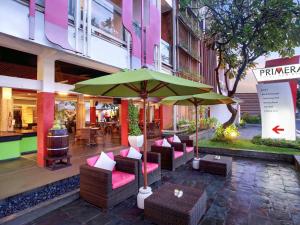 a patio with chairs and an umbrella in front of a building at Primera Hotel Seminyak in Seminyak