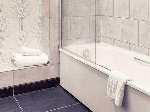 a bathroom with a tub and a shower with a towel at Mercure Thame Lambert Hotel in Chinnor
