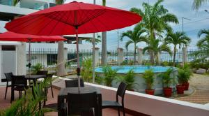 un patio con mesas, sombrillas rojas y una piscina en Hotel Casablanca CHIPIPE en Salinas