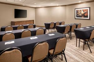 Staybridge Suites West Fort Worth, an IHG Hotel في فورت وورث: قاعة اجتماعات مع طاولات وكراسي وتلفزيون بشاشة مسطحة