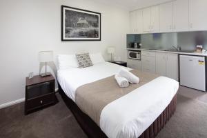 a bedroom with a large bed and a kitchen at Merivale Motel in Tumut