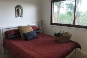 Byron Bay hinterland house - amazing sunset views! في Myocum: غرفة نوم مع سرير وملاءات حمراء ونافذة +42 صورة