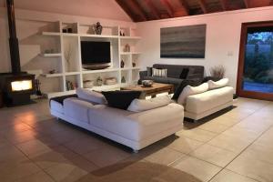 Byron Bay hinterland house - amazing sunset views! في Myocum: غرفة معيشة مع كنبتين بيضاء ومدفأة