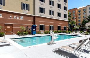 Candlewood Suites - Miami Exec Airport - Kendall, an IHG Hotel في كيندال: مسبح مع كراسي جلوس امام مبنى