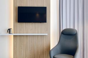 a room with a chair and a television on a wall at Holiday Inn Express - Rzeszow Airport, an IHG Hotel in Jasionka