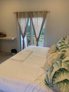 a white bed with pillows in front of a window at Crown Malapascua in Malapascua Island