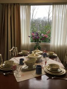 un tavolo con piatti e bicchieri e un vaso di fiori di Cornerhouse nr 75 a Heijen