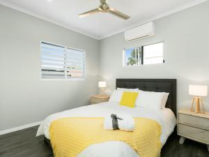 ein Schlafzimmer mit einem großen Bett mit gelben und weißen Kissen in der Unterkunft Estilo Bed and Breakfast in Cairns