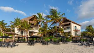 un complejo con mesas, sillas y palmeras en Tago Tulum by G Hotels, en Tulum