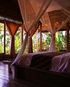 a bedroom with a bed with mosquito nets on it at Kidem Ubud Villas in Ubud