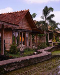 a wooden house with a canal in front of it at Kidem Ubud Villas in Ubud