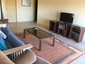 sala de estar con sofá y mesa de centro de cristal en Caretakers Cottage Budget Accommodation, en Denham