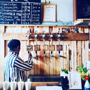 a person standing in a restaurant with a chalkboard at Bakushuku Den Guest House Brew in Matsuyama