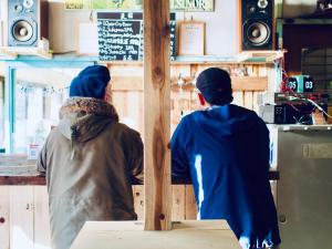 two people sitting at a counter in a restaurant at Bakushuku Den Guest House Brew in Matsuyama