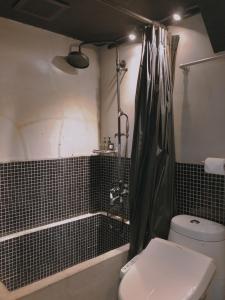a bathroom with a black shower curtain and a toilet at Just Inn in Taipei