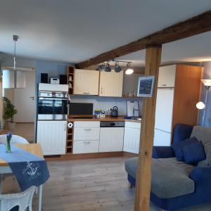 NiebyにあるOstseeurlaub-Asmussen Niebyの白いキャビネットと青いソファ付きのキッチンが備わります。