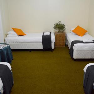 Habitación con 3 camas con almohadas de color naranja en Shamrock Hotel Motel Temora, en Temora