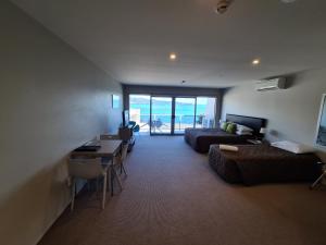 Te Kaha Beach Hotel في Te Kaha: غرفة معيشة مع أريكة وسرير وطاولة