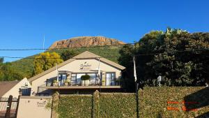a house with a fence in front of a mountain at Pumleni Guesthouse in Hartbeespoort