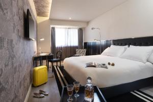 a hotel room with a bed and a desk with a yellow suitcase at NYX Tel Aviv in Tel Aviv