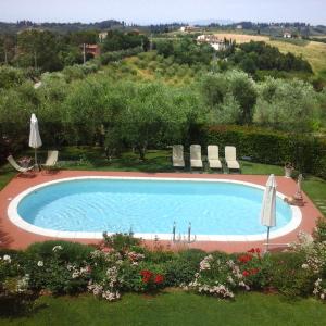 una piscina en un patio con sillas y sombrillas en Villa Antica Sosta Renai, en Castelfiorentino