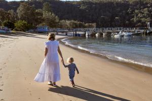 a woman and a child walking on the beach at Cape Mackerel Cabin with Magic Palm Beach & Pittwater Views in Great Mackerel Beach
