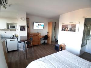 a bedroom with a bed and a kitchen with a desk at Studio Santa Monica - Climatisé - Piscine - Parking in Toulouse