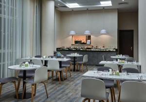 uma sala de jantar com mesas e cadeiras e uma cozinha em TIME Express Hotel Al Khan em Sharjah