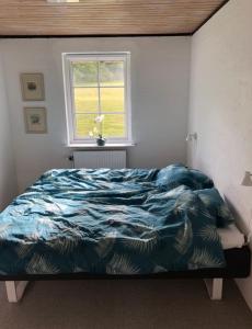 ein Schlafzimmer mit einem Bett mit blauer Decke und einem Fenster in der Unterkunft Ellemose Bed and Breakfast in Lemvig