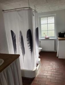 un baño con una pared con plumas. en Ellemose Bed and Breakfast en Lemvig