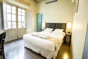 1 dormitorio con 1 cama grande con sábanas blancas en Hotel Boutique Casas de Santa Cruz en Sevilla
