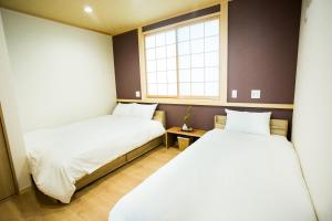 two beds in a small room with a window at Oyado Toshi in Kyoto