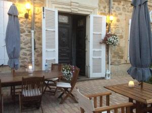 a patio with a table and chairs and shuttered doors at Le Neptune in Le Somail