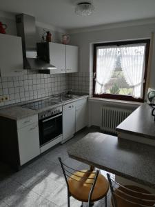 a kitchen with white appliances and a table with chairs at Ferienwohnungen Blum in Kelberg