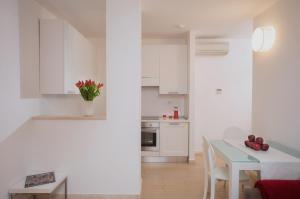 een keuken met witte kasten en een tafel met rode bloemen bij Di Sabatino Resort - Suite Apartments & Spa in Ascoli Piceno